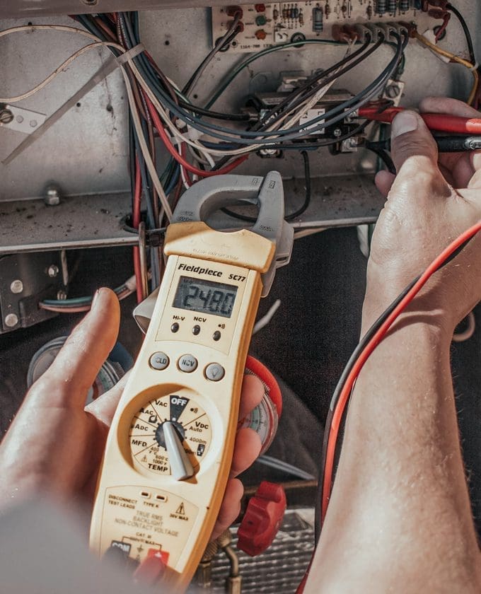 Technician checking voltage of heating unit.