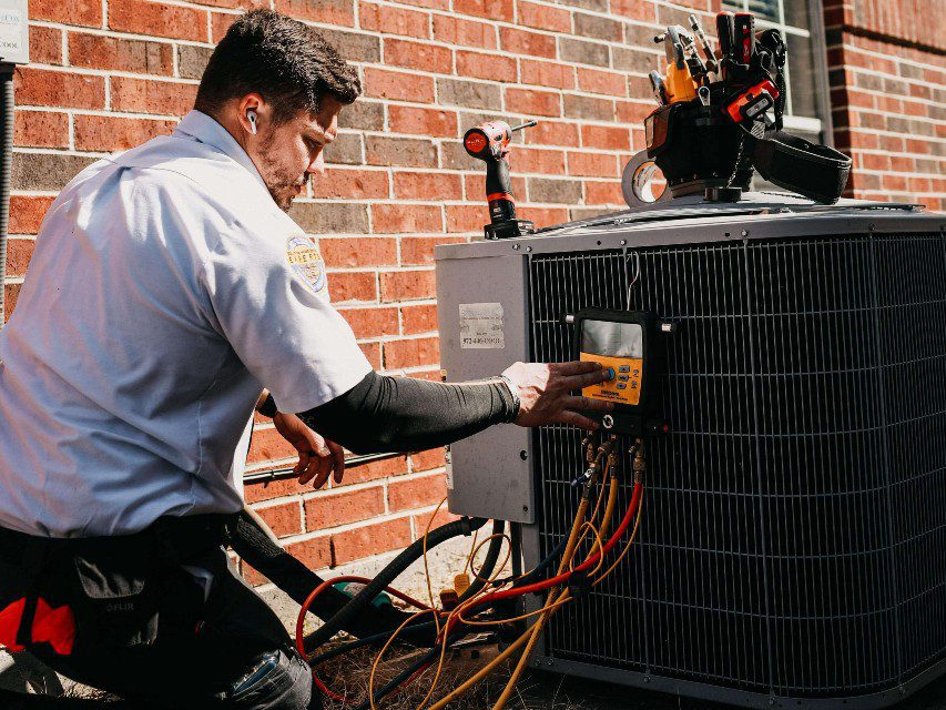 air conditioning technician repairing an HVAC unit